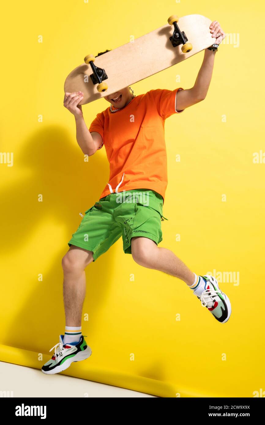 Holding the skateboard bouncing young man Stock Photo
