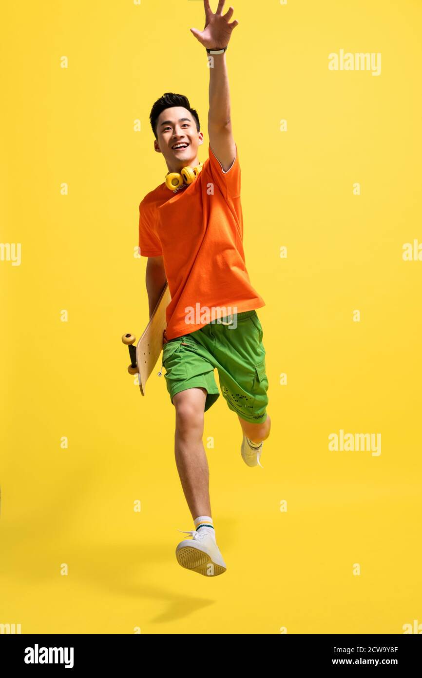 Holding a skateboard bouncing happy young man Stock Photo