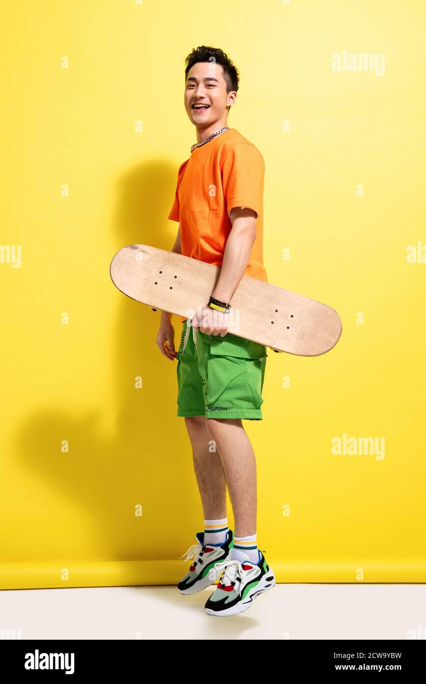 Holding a skateboard happy young man Stock Photo