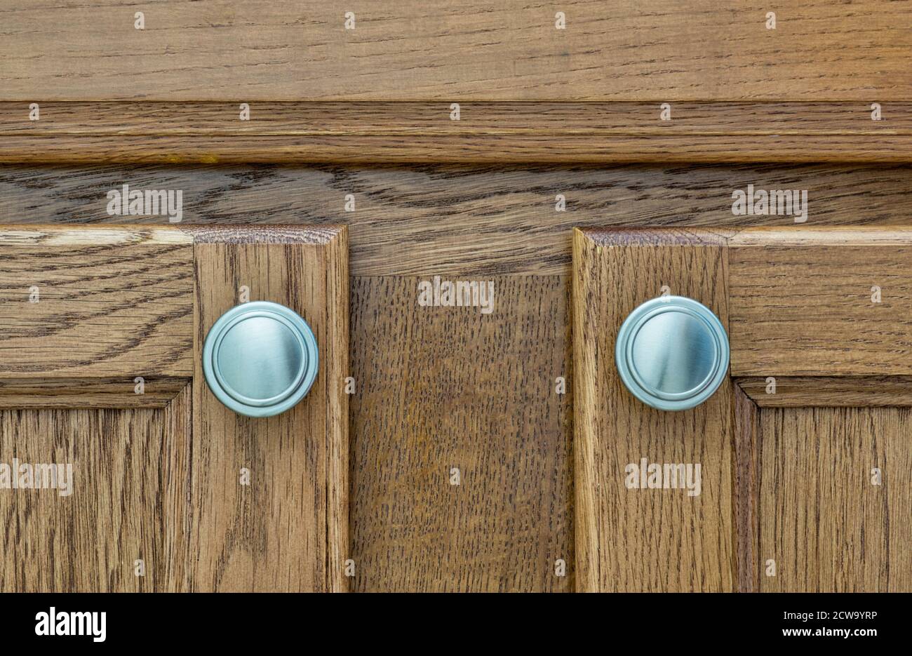 Brown wooden cupboard doors with silver handles closeup, wood stain color swatch. Stock Photo