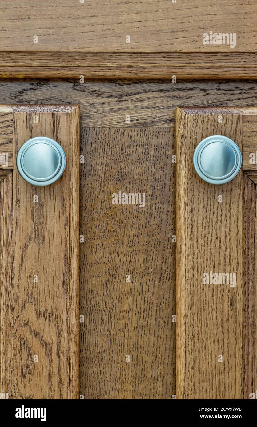 Brown wooden cupboard doors with silver handles closeup, wood stain color swatch in vertical format. Stock Photo