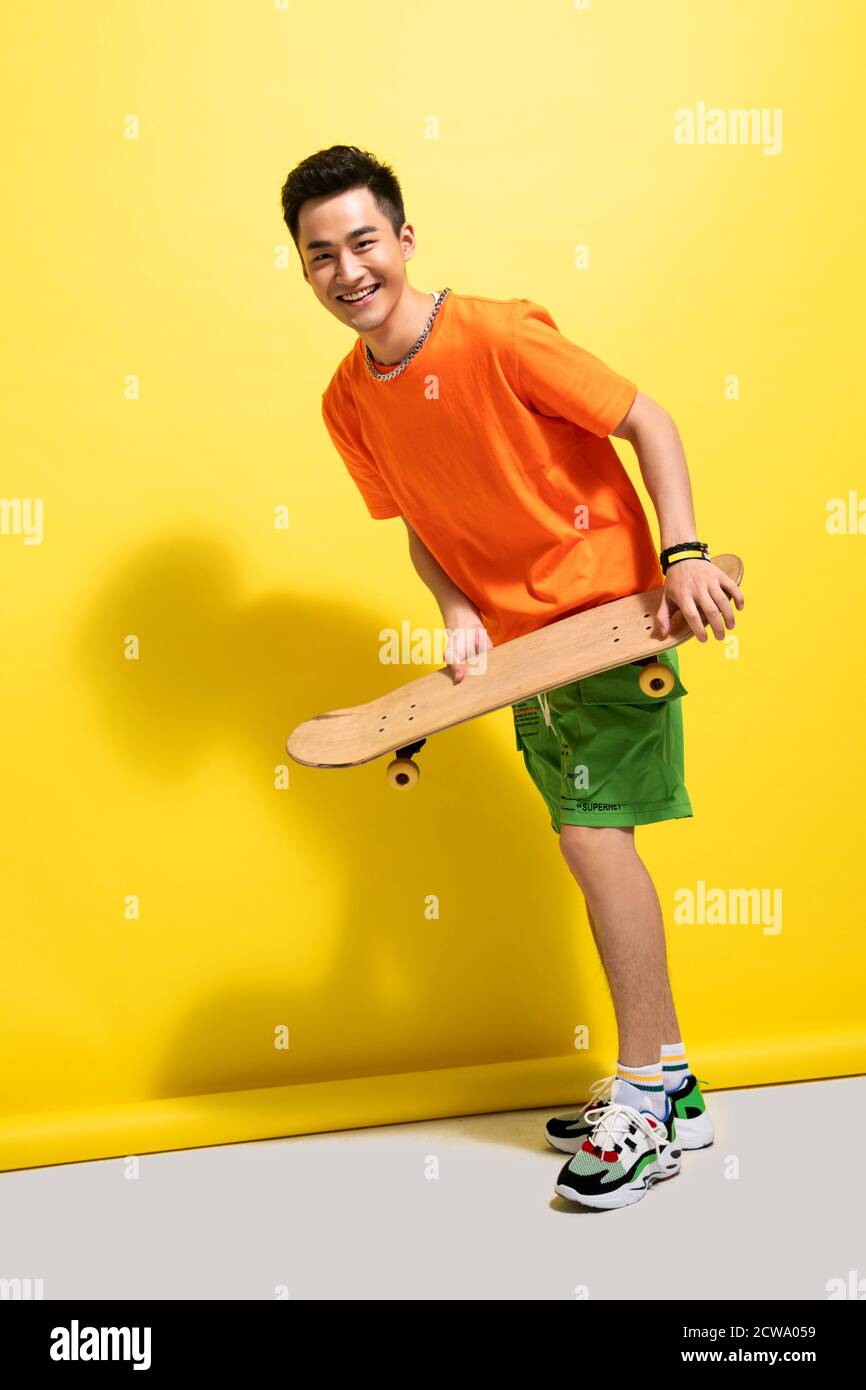 Holding a skateboard happy young man Stock Photo