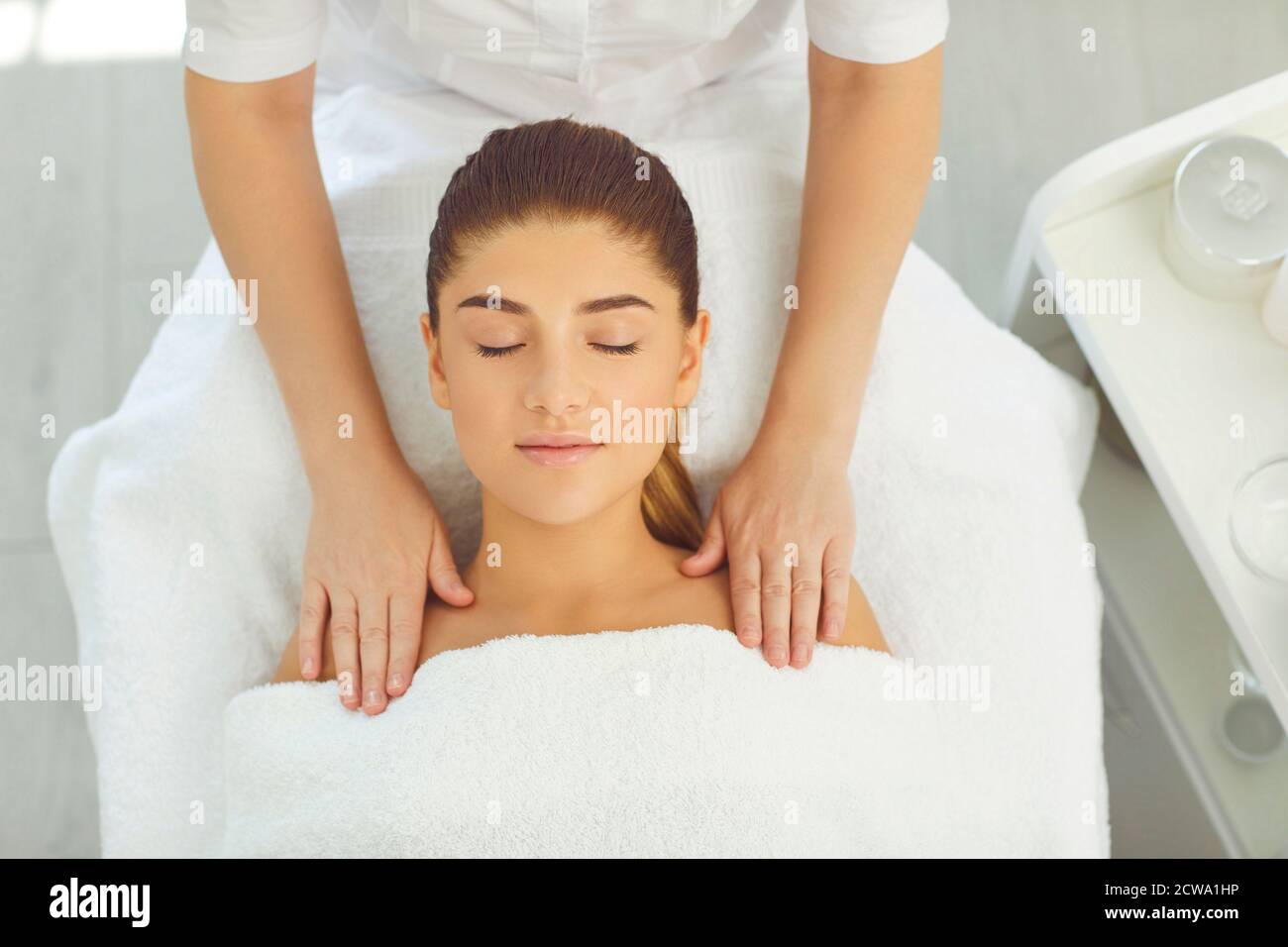 Hands Of Cosmetologist Making Facial And Shoulders Massage For Smiling Woman In Wellness Beauty