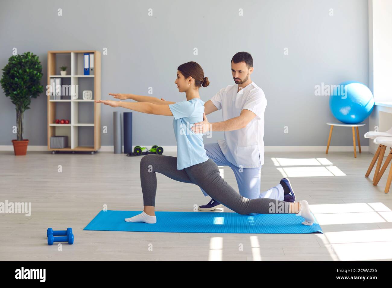 Physiotherapist in health center helping female athlete recover after