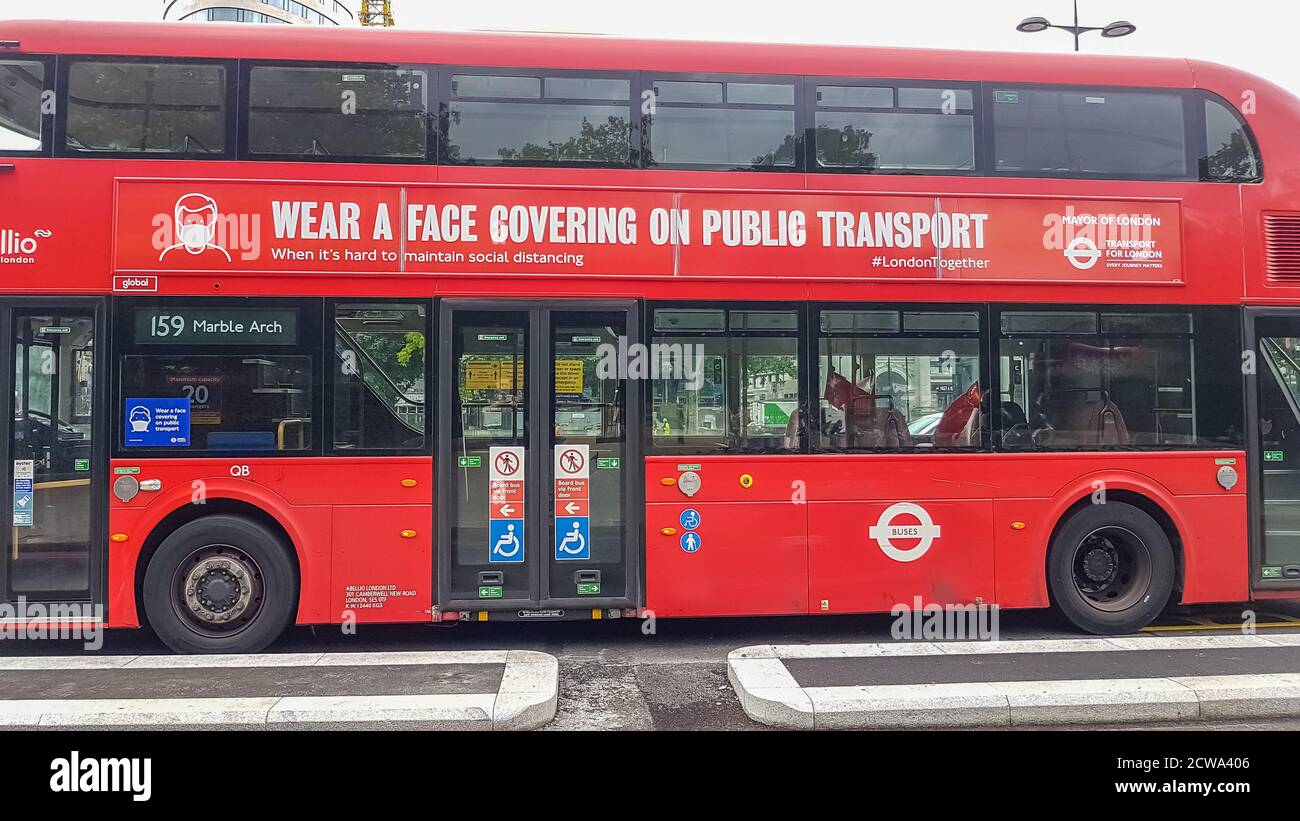 London, UK - July 8, 2020: Modern red double-decker bus is waiting for people in central London. It says on it - Wear a face covering on public transp Stock Photo