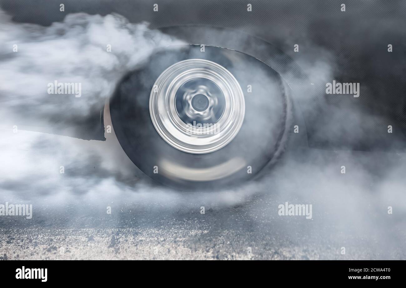 Drag racing car burns rubber off its tires in preparation for the race ...