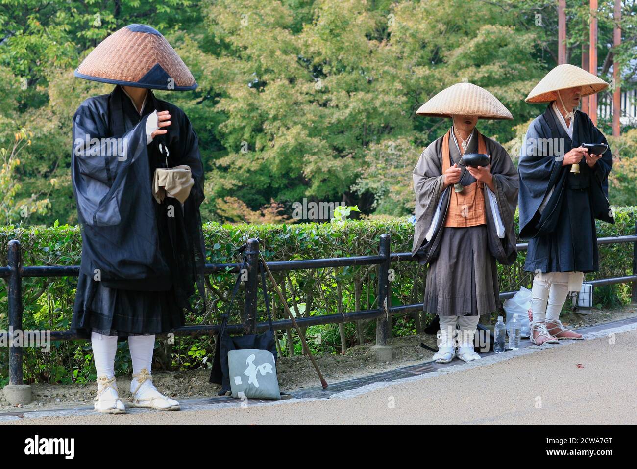 Kyoto, Japan - November 23, 2007: Zen Buddhist monks practice takuhatsu in  traditional robes and straw hats. He exchange chanting of sutras for donat Stock Photo