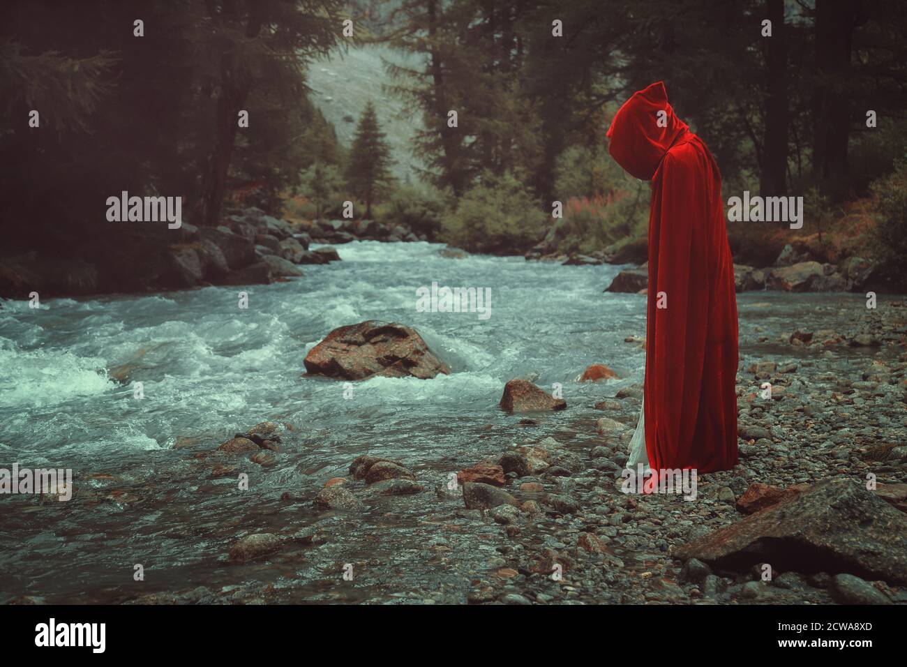 Mysterious red cloaked figure by mountain stream Stock Photo