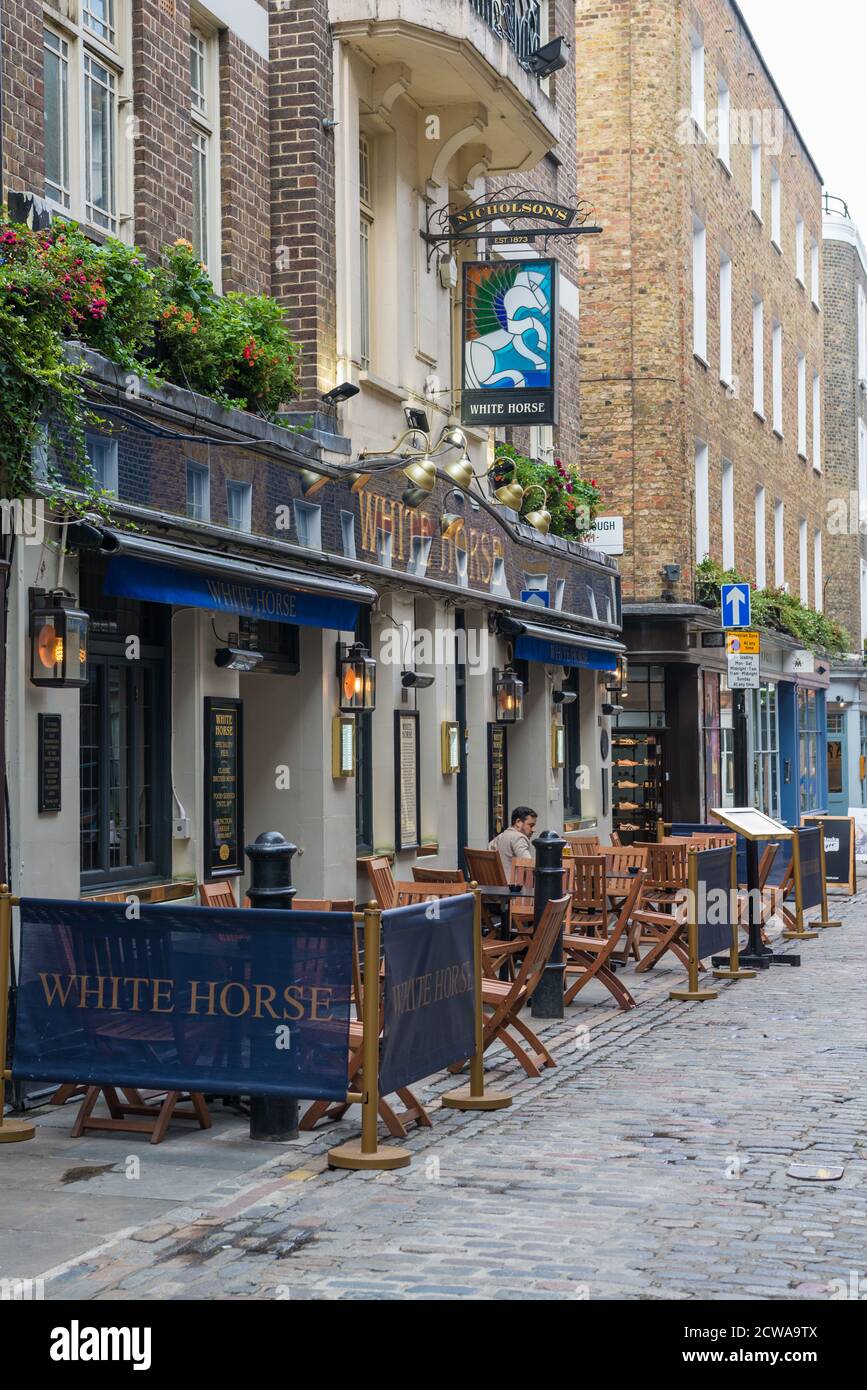 A lone man sitting at a pavement table outside the White Horse pub in Newburgh Street, Soho, London, England, UK Stock Photo