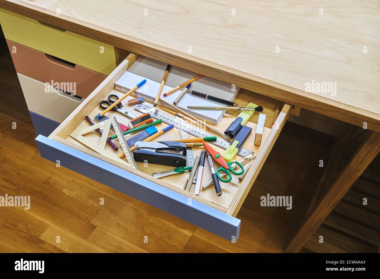 Open drawer of modern desk with unsorted stationery not ready for school studies Stock Photo
