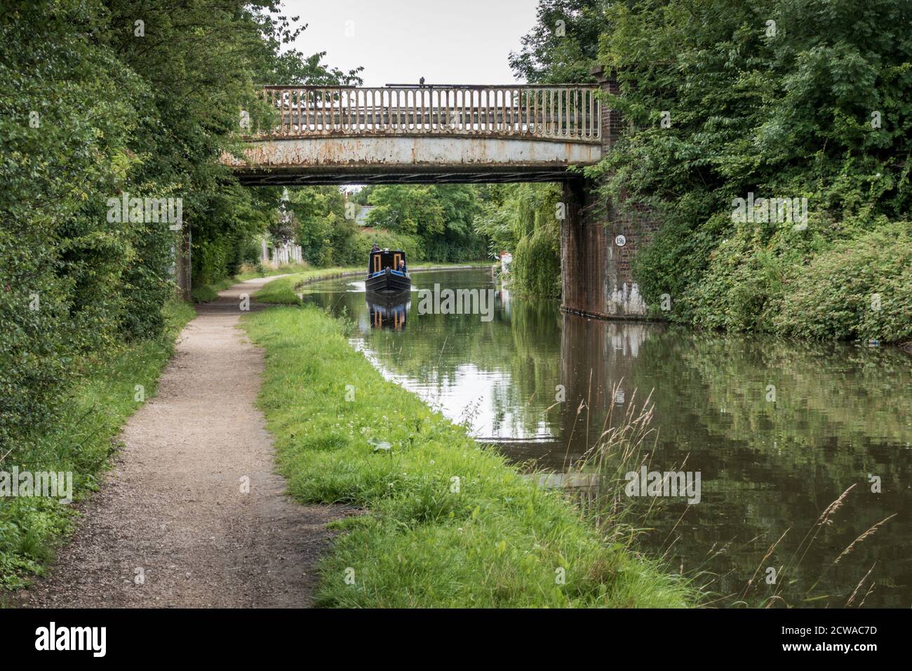 narrowboat on the Coventry Canal in Nuneaton, sailing towards railway bridge carrying the line between Nuneaton and Coventry. Stock Photo