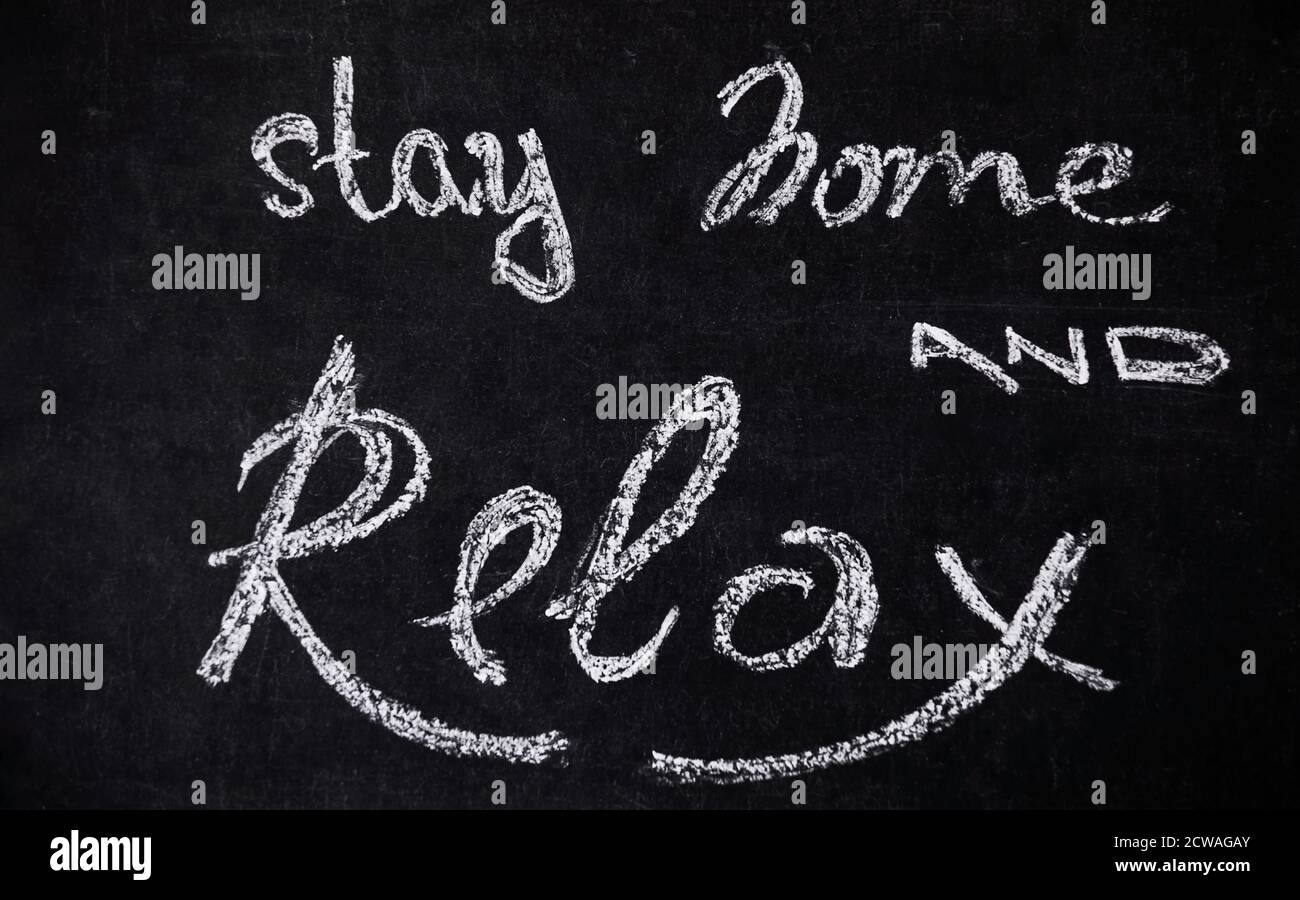 Stay home quarantine isolation period concept. Chalkboard with handwritten chalk lettering Stay home and relax. Stock Photo