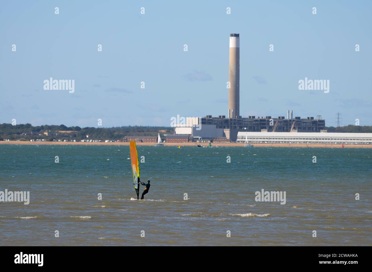 Windsurfer and Fawley power station. The power station in the background is being dismantled, showing the exposed internal structure. Stock Photo