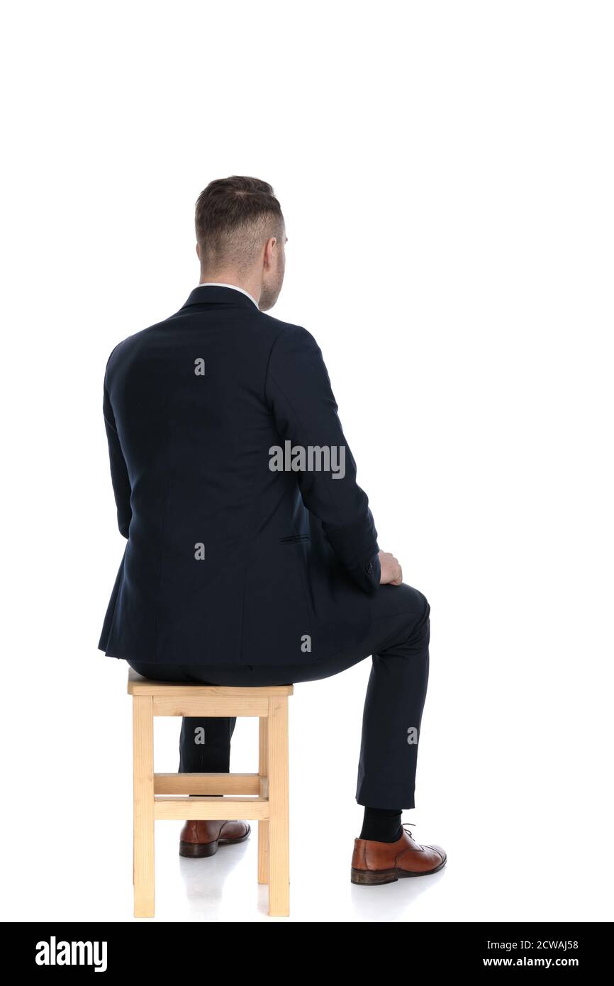 Rear view of a handsome businessman sitting on a chair on white studio ...