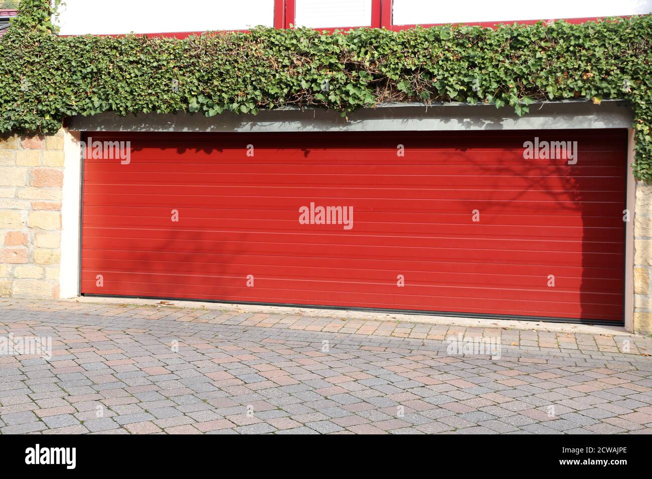 High-quality red garage door (sectional door) next to a residential building Stock Photo
