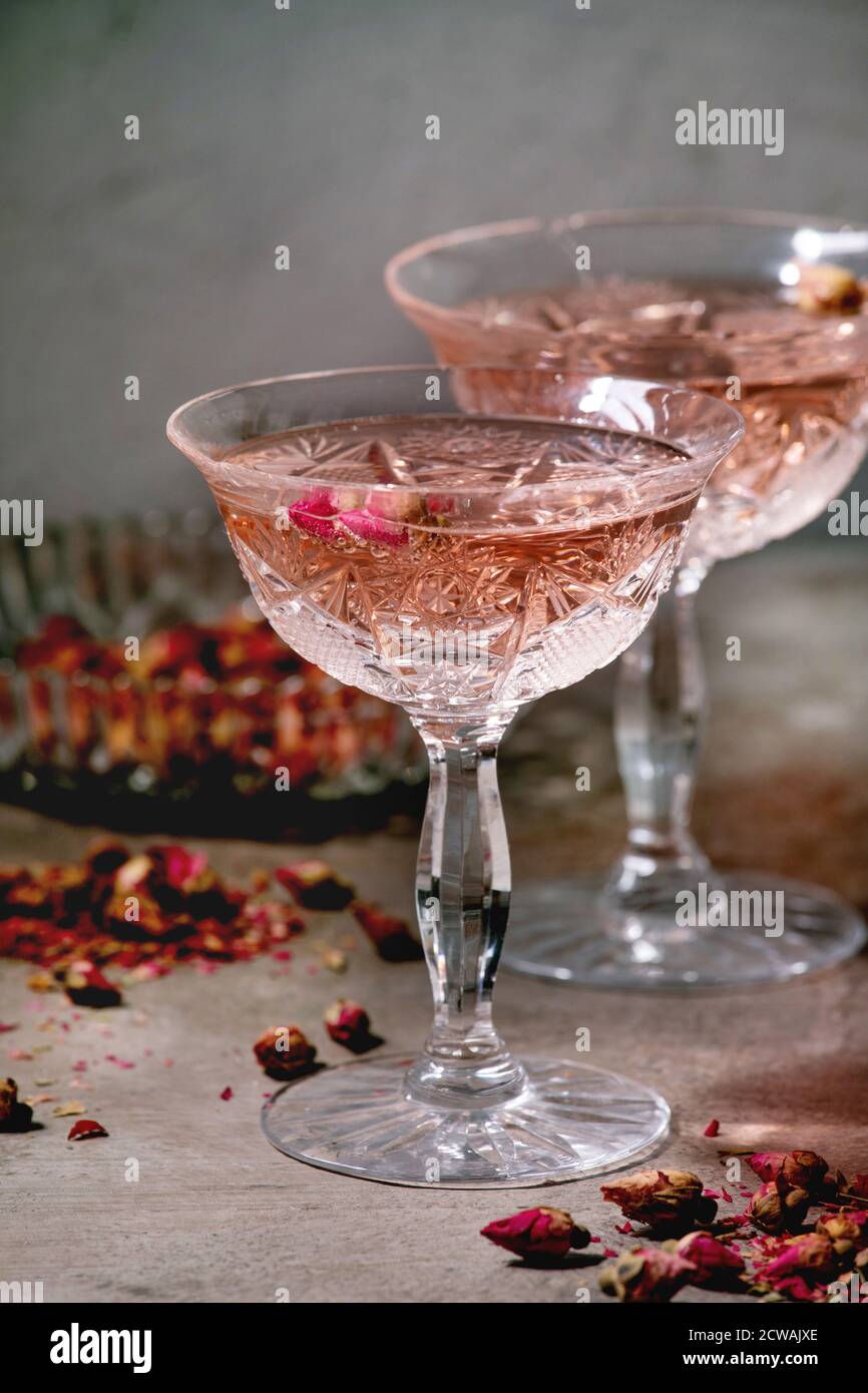 Crystal vintage glasses of pink rose champagne, cider or lemonade with dry  rose buds. Grey texture background Stock Photo - Alamy, image size:866x1390