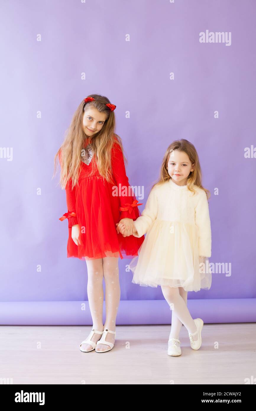 Two little girls in a red and white dress hold hands Stock Photo - Alamy