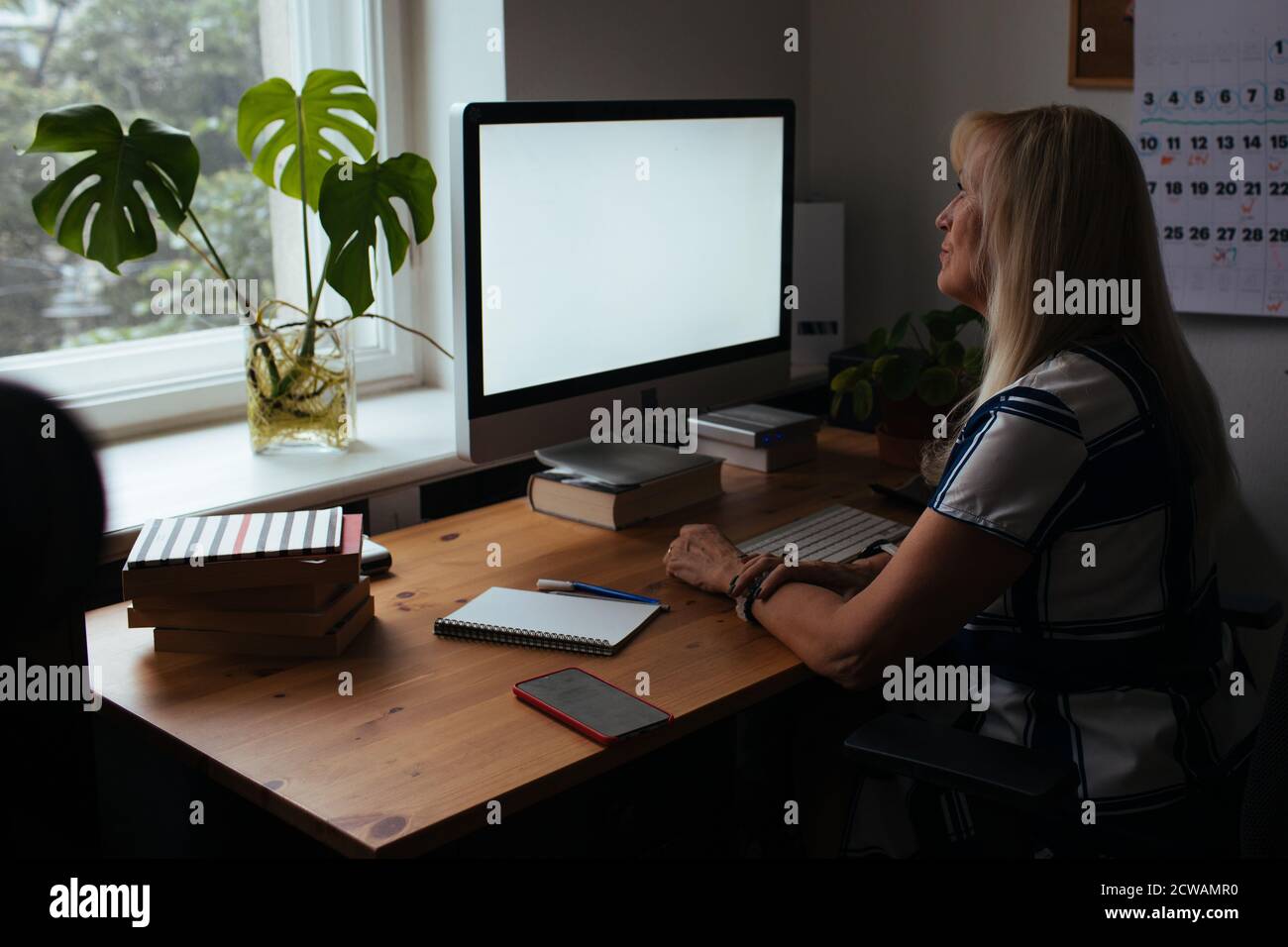 Online training teacher. Day to day new normal office Work from home. Smiling mature woman having video call via laptop in the studio flat office. Stock Photo
