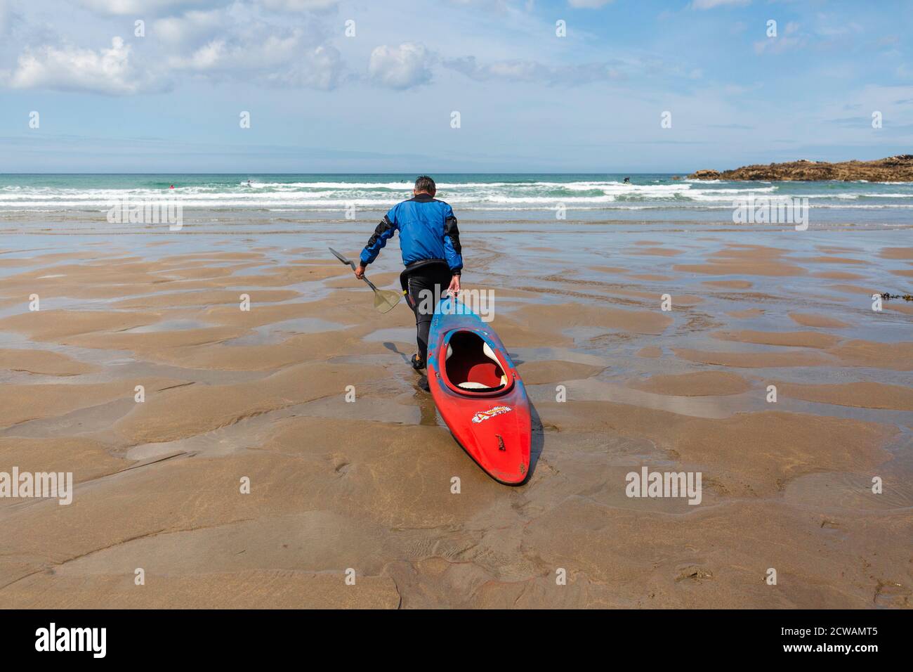 Man pulling his canoe along the beach towards the sea Stock Photo
