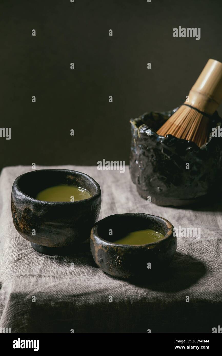 Japanese matcha green tea in two wabi sabi cups, bamboo whisk on grey linen table cloth. Stock Photo
