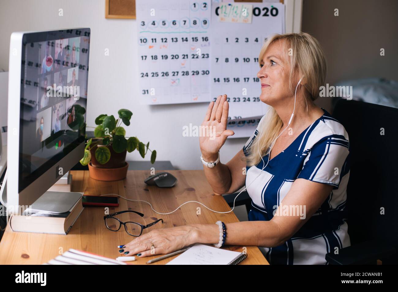 Online training teacher. Day to day new normal office Work from home. Smiling mature woman having video call via laptop in the studio flat office. Stock Photo