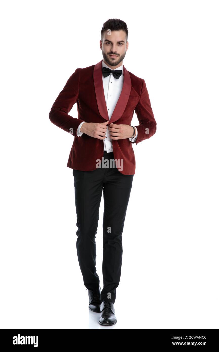 smiling young man in red velvet tuxedo adjusting coat and walking isolated  on white background, full body Stock Photo - Alamy