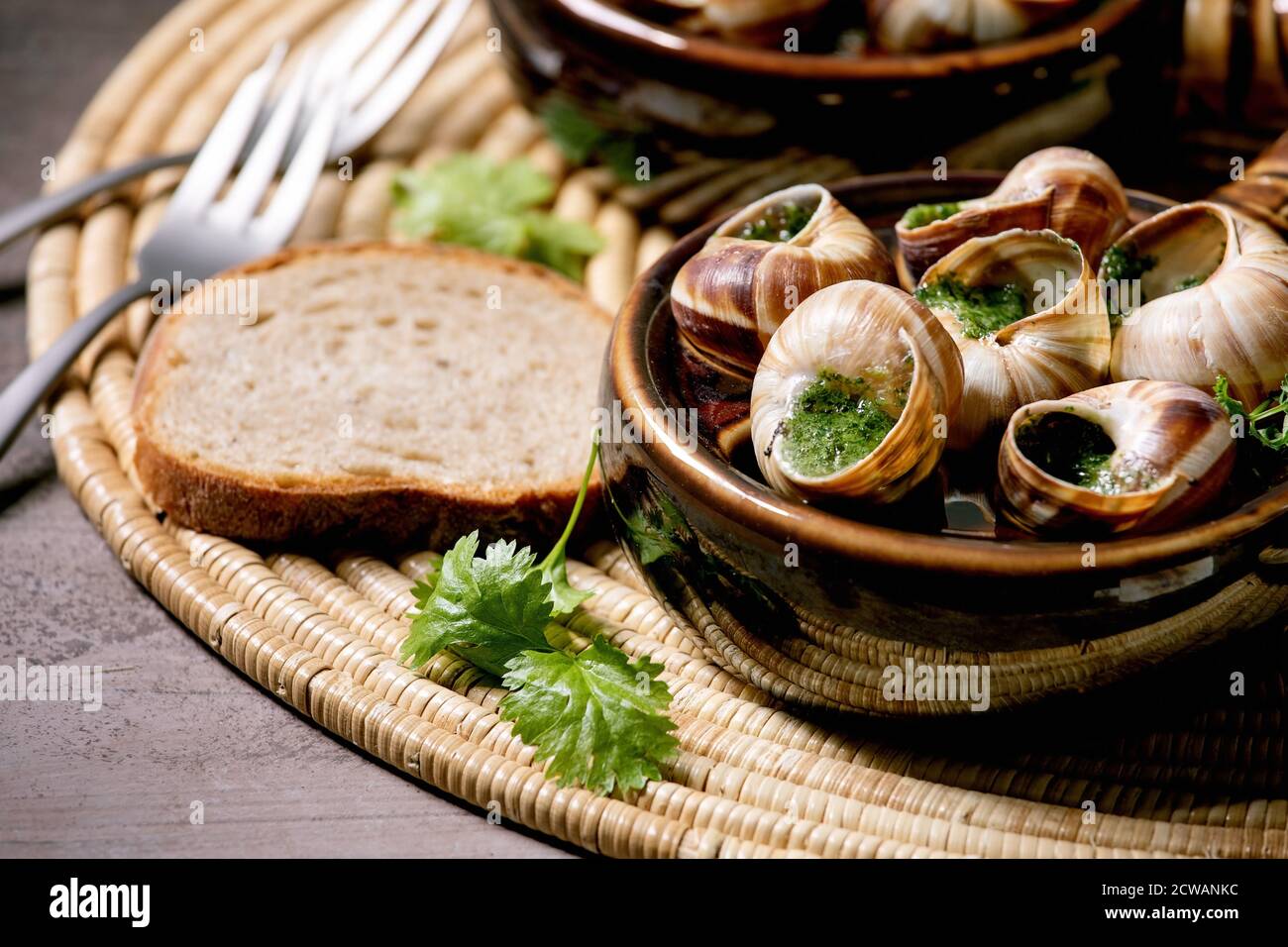 Escargots de Bourgogne - Snails with herbs butter, gourmet dish, in two  traditional ceramic pans with coriander and bread on straw napkin. Close up  Stock Photo - Alamy
