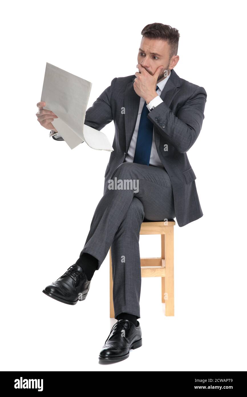shocked young businessman covering mouth with hand and reading ...