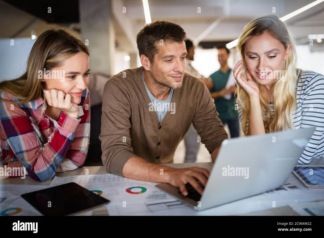 Young architect colleagues are analyzing blueprints while working on a new project Stock Photo
