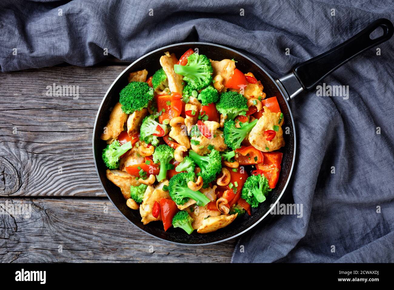 Cashew chicken with veggies stir-fry: broccoli, bell pepper, hot red chili,  and soya sauce served on a skillet on a rustic wooden background, top view  Stock Photo - Alamy