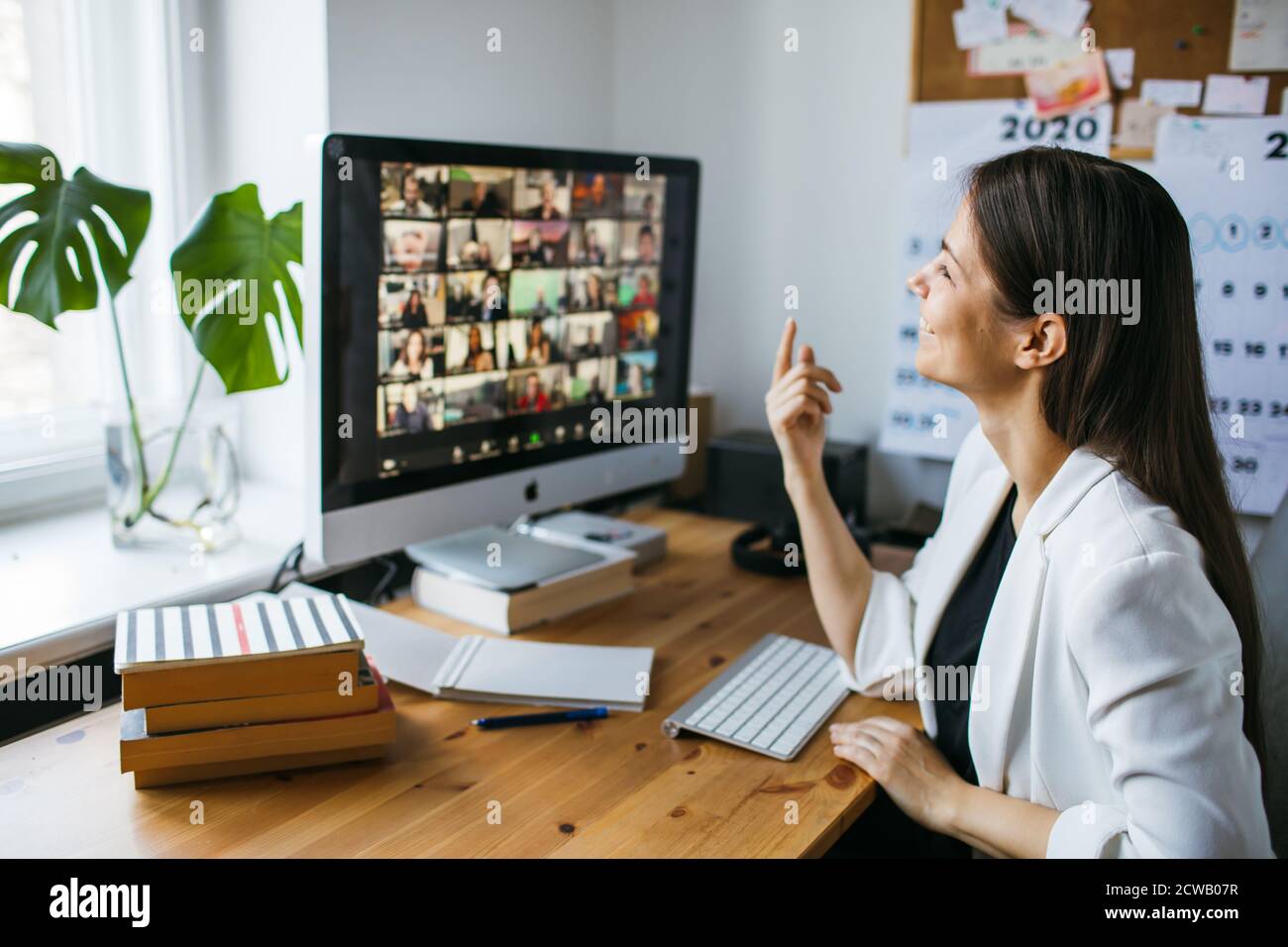 Smiling woman having video call via computer in the home office. Online team meeting video conference calling from home. Businesswoman teleworking Stock Photo