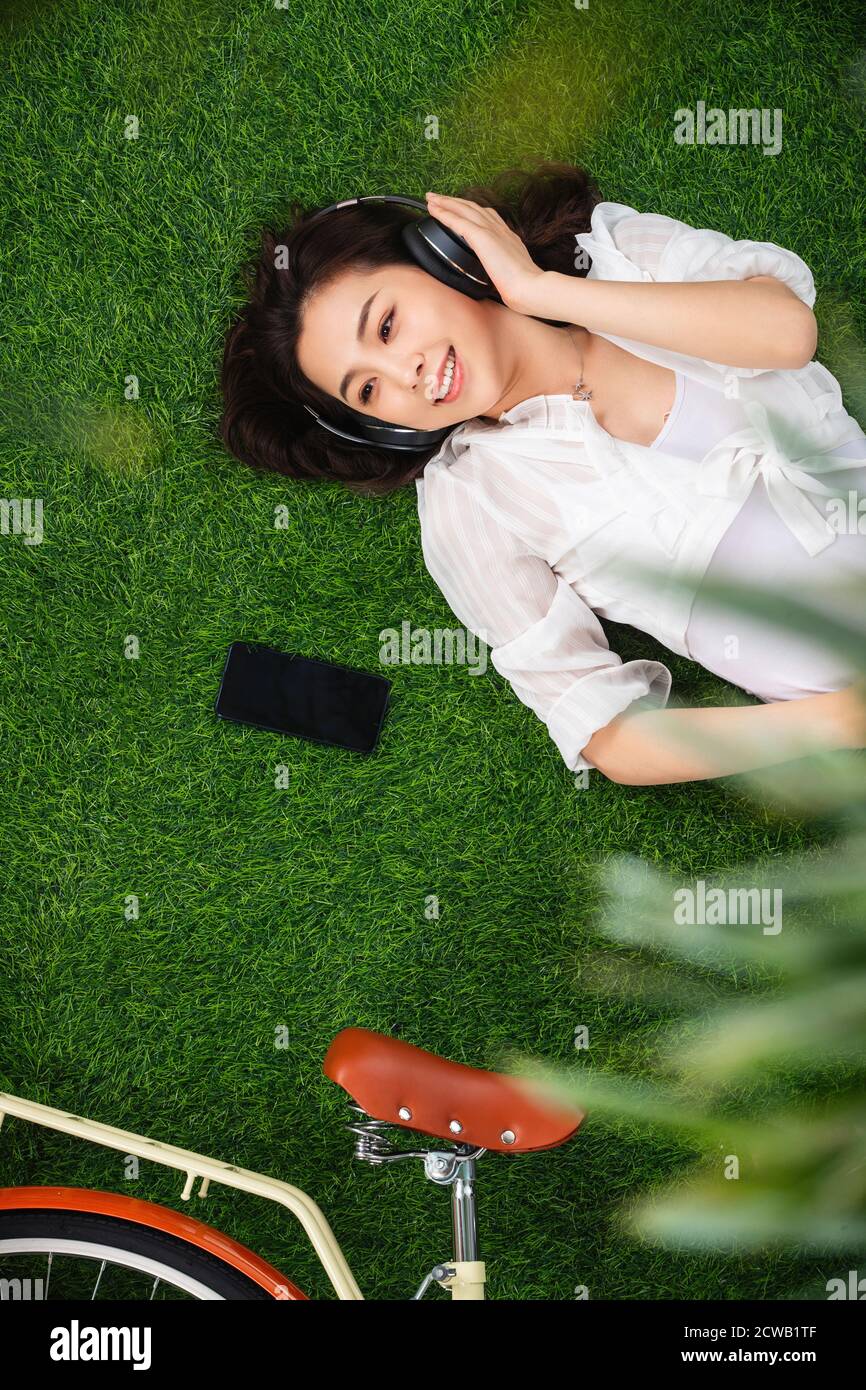Young woman lying on the grass to listen to music Stock Photo - Alamy