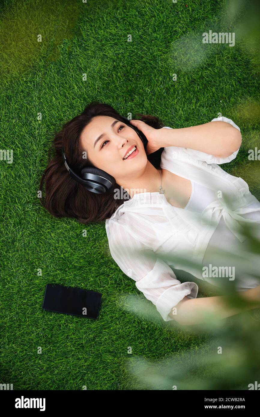 Young woman lying on the grass to listen to music Stock Photo - Alamy