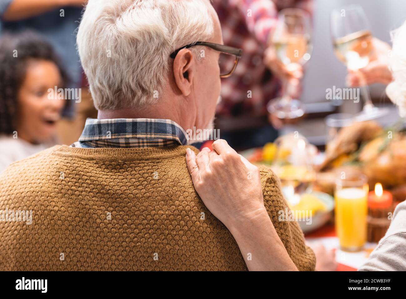 Selective focus of elderly woman embracing husband while celebrating thanksgiving with family Stock Photo