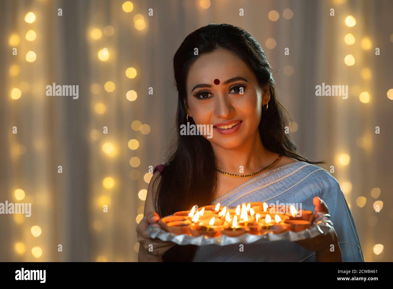 Woman smiling with a plate of diyas in her hand Stock Photo