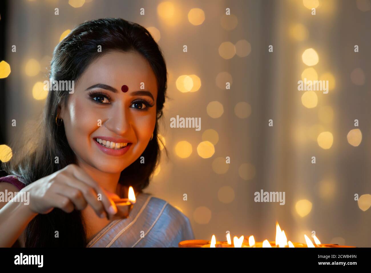 Woman smiling with a diya in her hand Stock Photo