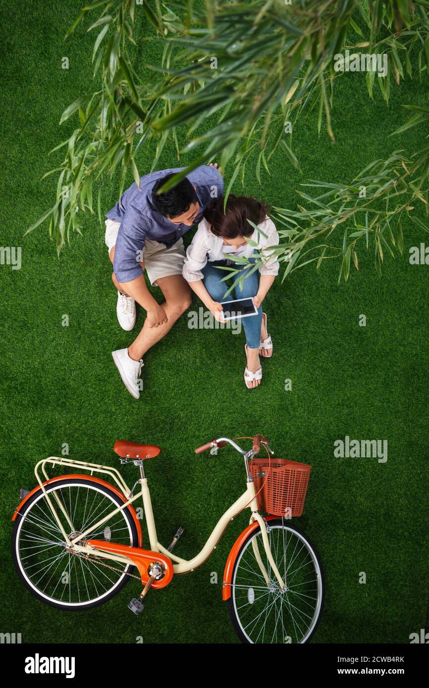 Young couples sitting on the grass to use tablet Stock Photo - Alamy