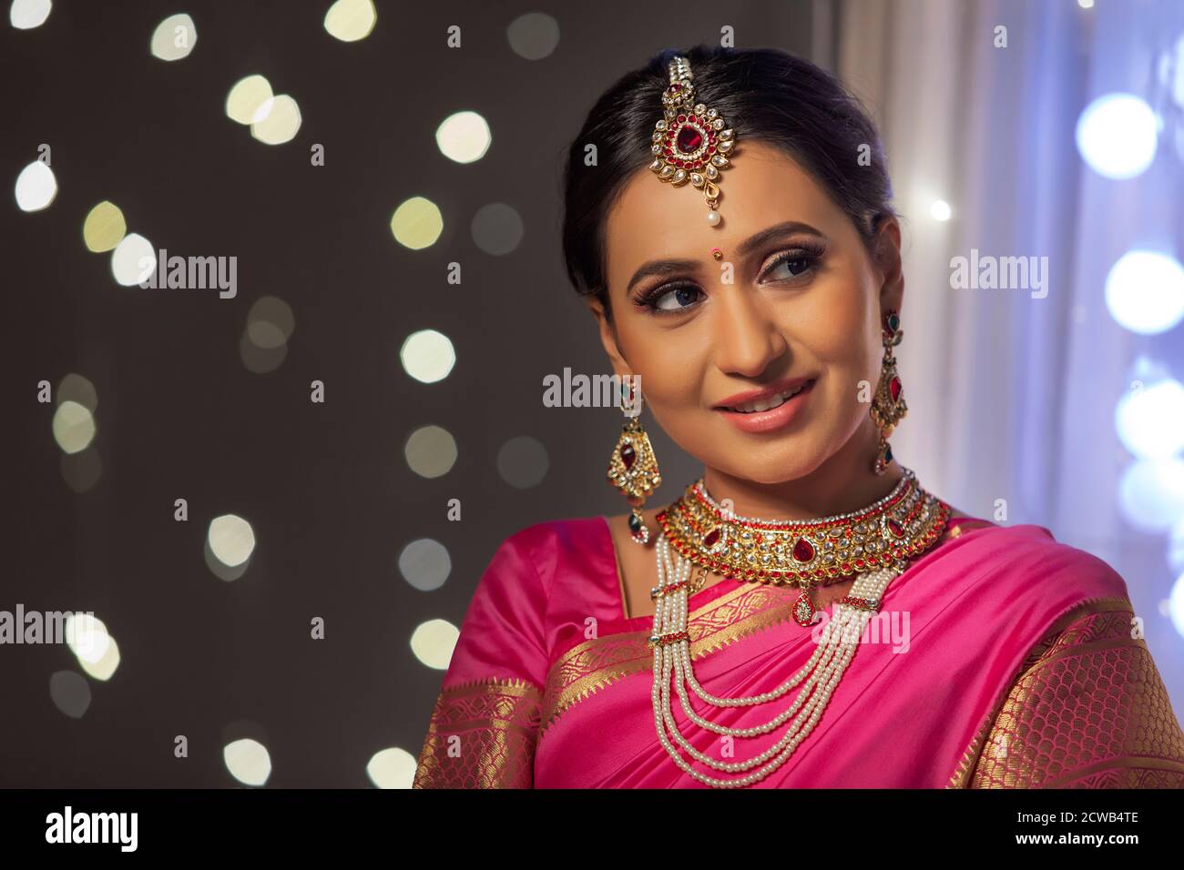 Woman in a pink saree looking sideways with a smile on her face Stock Photo