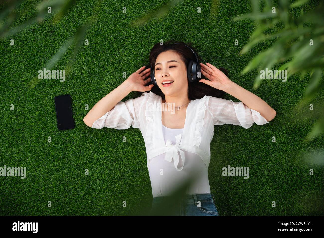 Young woman lying on the grass to listen to music Stock Photo - Alamy