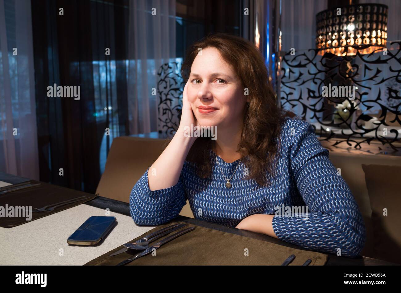 Smiling European woman waits a dish in a restaurant, close-up portrait with selective focus Stock Photo
