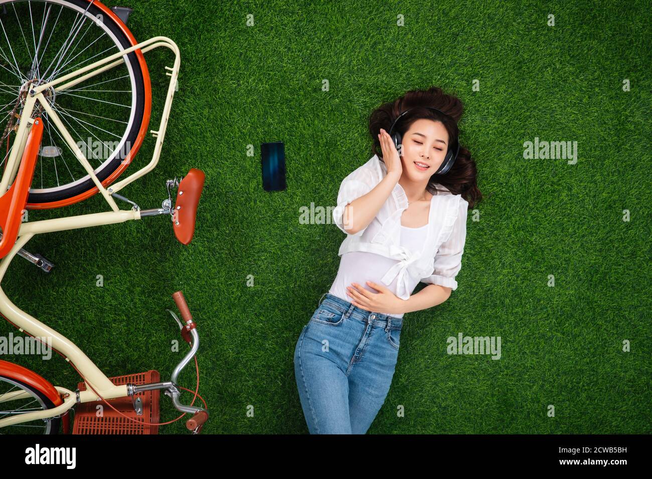 Young woman lying on the grass to listen to music Stock Photo - Alamy