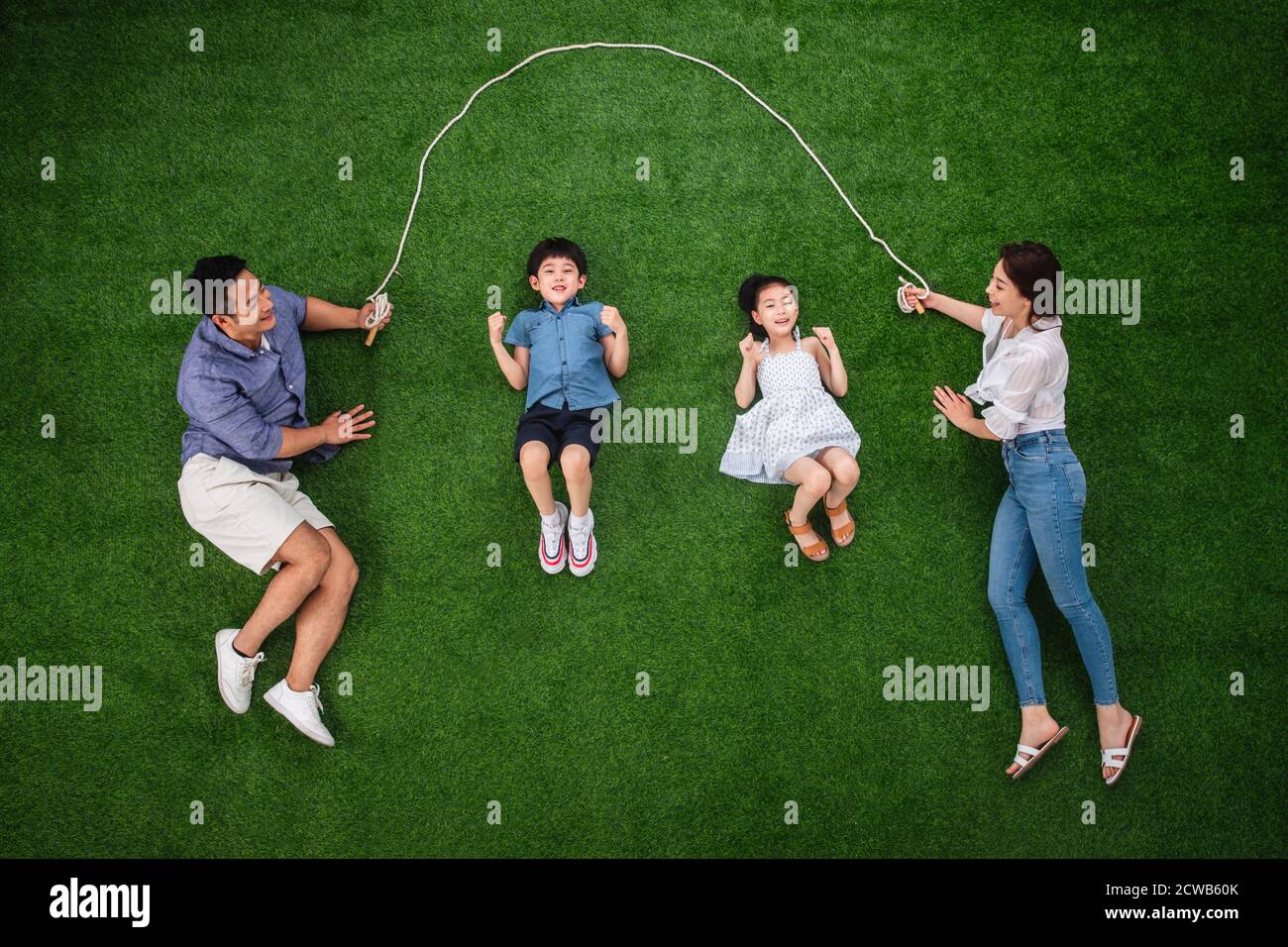 The happy family of four rope jumping on the grass Stock Photo Alamy