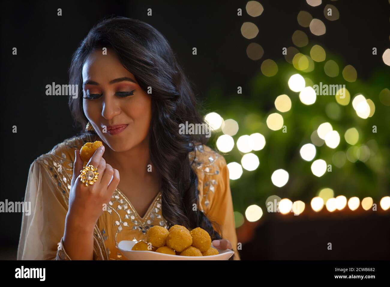 Woman looking at a ladoo after taking a bite Stock Photo
