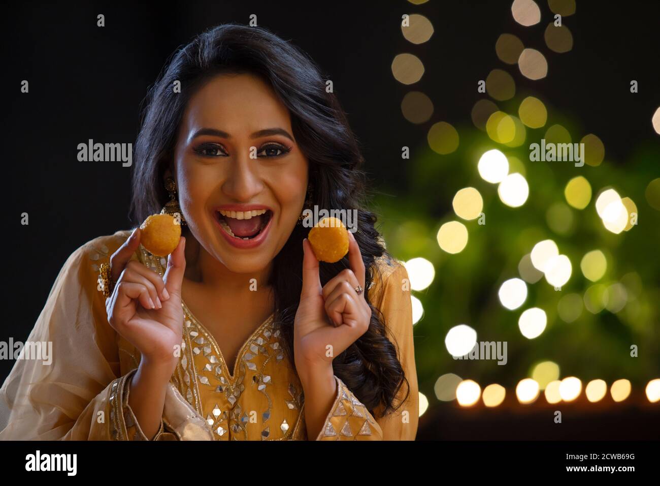 Woman smiling with ladoos in her hands on the occasion of Diwali Stock Photo