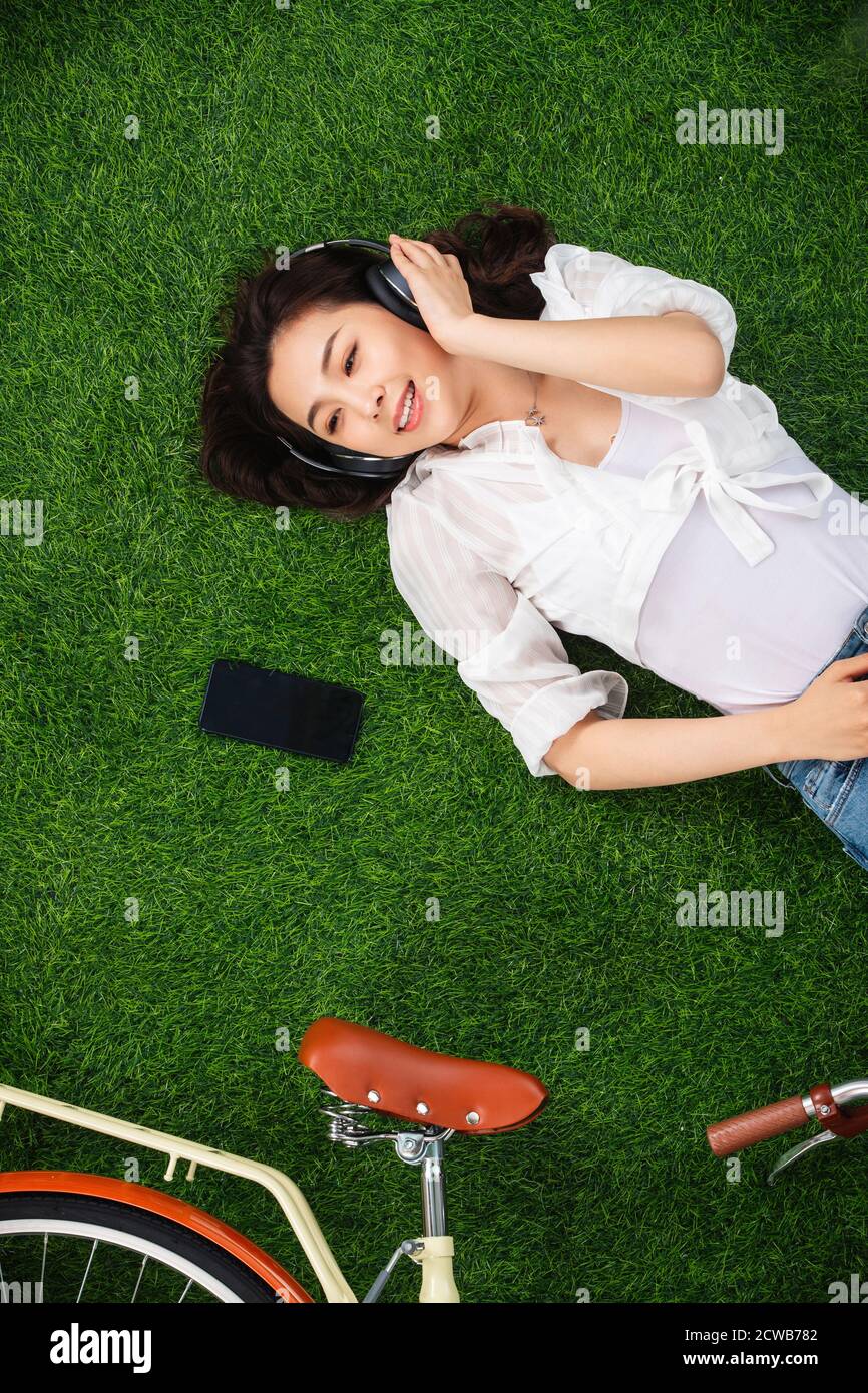 Young woman lying on the grass to listen to music Stock Photo - Alamy
