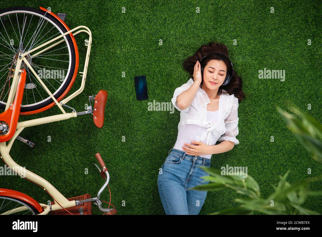 Young woman lying on the grass to listen to music Stock Photo - Alamy