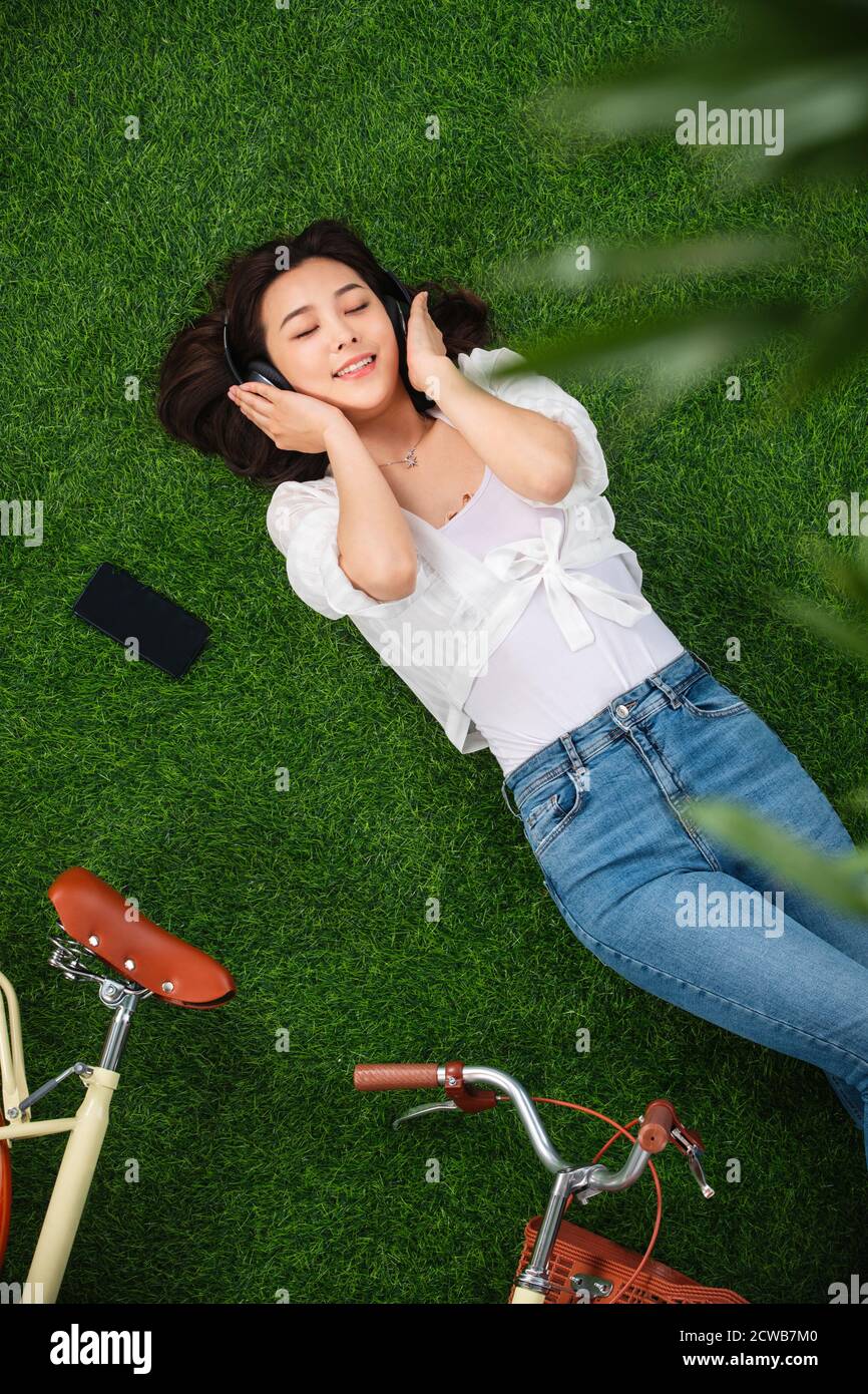 Young woman lying on the grass to listen to music Stock Photo - Alamy