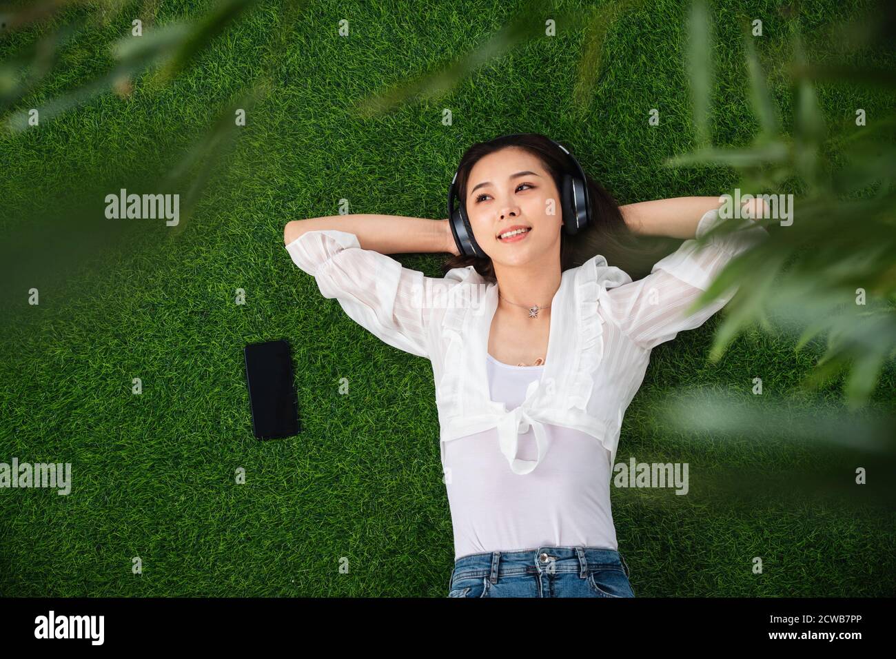 Young woman lying on the grass to listen to music Stock Photo - Alamy