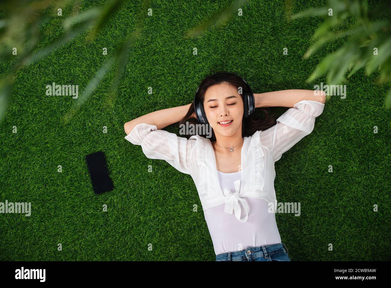Young woman lying on the grass to listen to music Stock Photo - Alamy