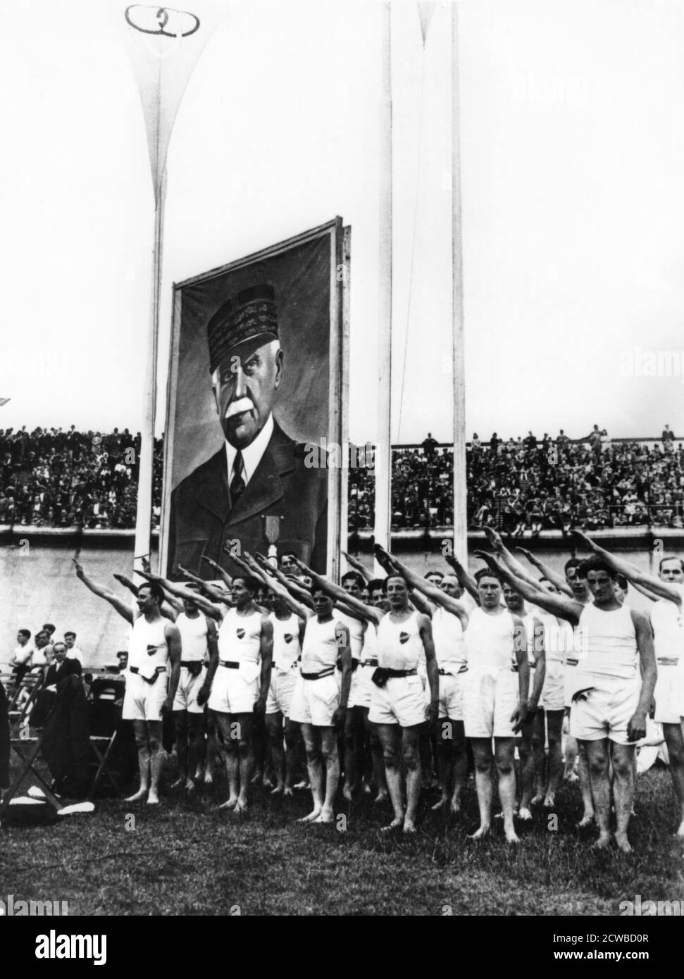 Athletes giving the fascist salute at the Parc des Princes, Paris, 1941. A massive portrait of Marshal Petain, head of the Vichy regime stands behind them. The photographer is unknown. Stock Photo